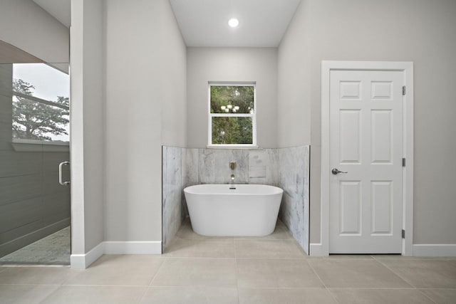 full bath with tile patterned flooring, a wainscoted wall, tile walls, a freestanding bath, and a stall shower