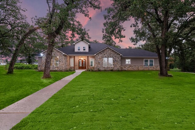 view of front of home with stone siding, a front lawn, and stucco siding