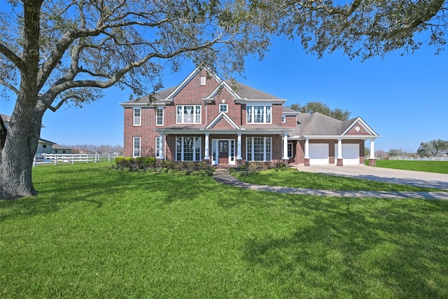 view of front of property with a garage, driveway, fence, a front yard, and brick siding