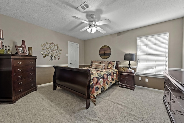 carpeted bedroom featuring ceiling fan and a textured ceiling