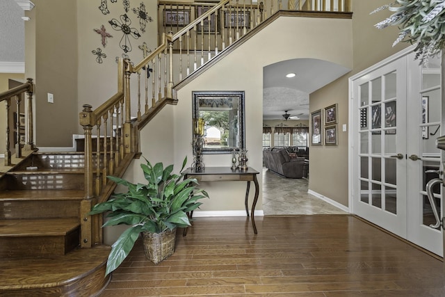 stairs with hardwood / wood-style floors, a high ceiling, ceiling fan, a textured ceiling, and french doors