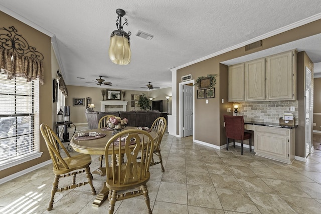 tiled dining area with crown molding, built in desk, a textured ceiling, and ceiling fan