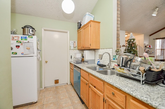 kitchen with sink, light tile patterned floors, dishwasher, white refrigerator, and tasteful backsplash