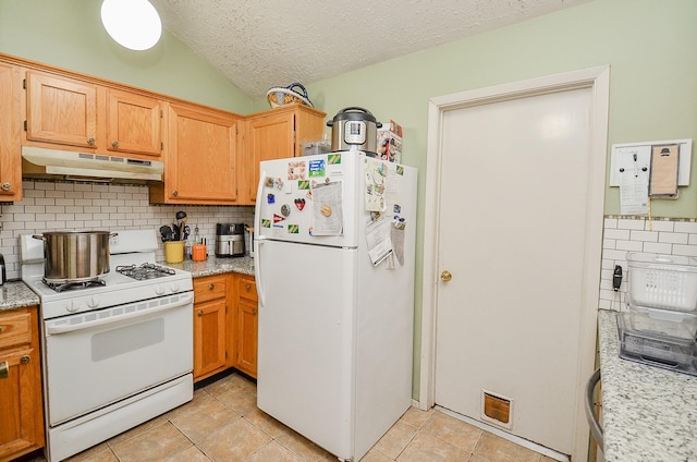 kitchen with tasteful backsplash, light tile patterned floors, a textured ceiling, and white appliances