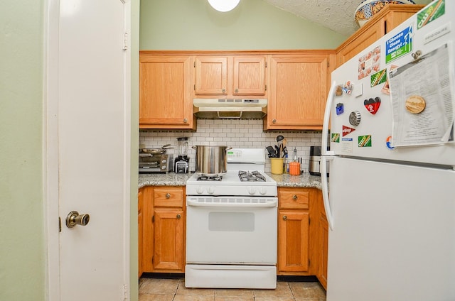 kitchen featuring light tile patterned flooring, white appliances, vaulted ceiling, and backsplash