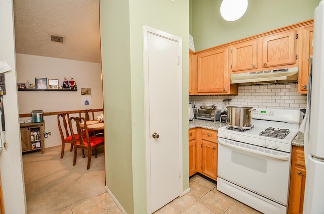 kitchen with white appliances, light tile patterned floors, a textured ceiling, and backsplash