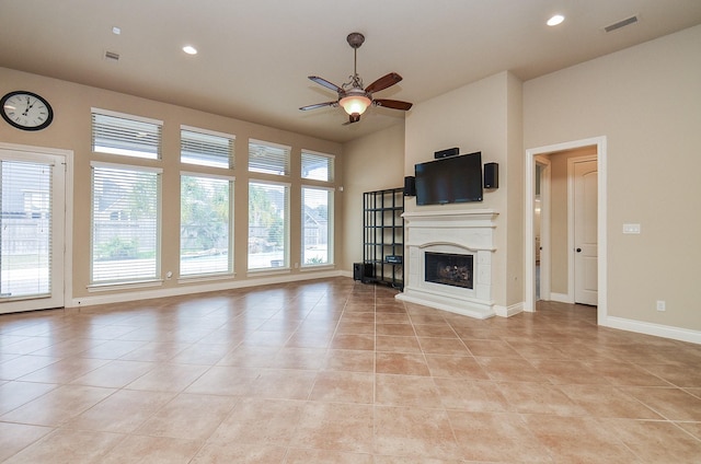 unfurnished living room featuring light tile patterned floors, a towering ceiling, plenty of natural light, and ceiling fan