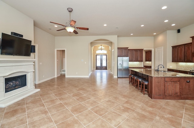 kitchen with stainless steel refrigerator with ice dispenser, light stone countertops, light tile patterned floors, and decorative backsplash