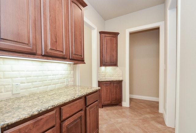 kitchen with decorative backsplash, light stone countertops, and light tile patterned flooring