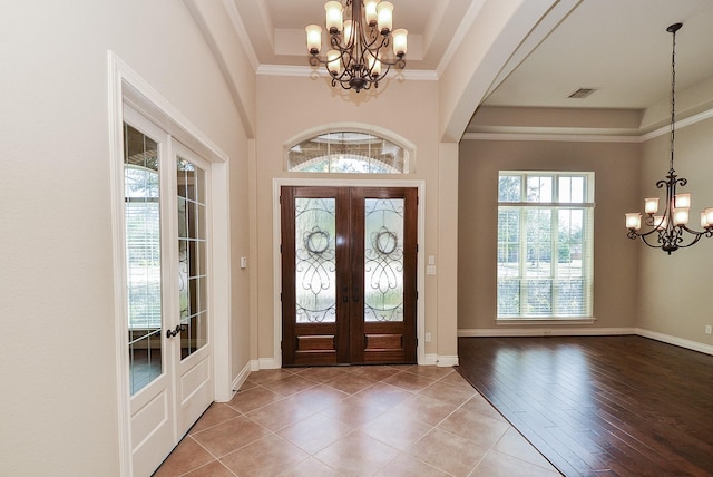 entrance foyer with hardwood / wood-style flooring, a tray ceiling, ornamental molding, french doors, and a chandelier