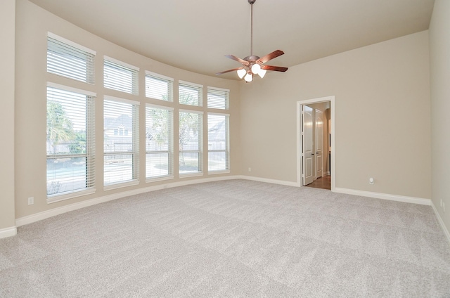 empty room with a wealth of natural light, light colored carpet, and ceiling fan