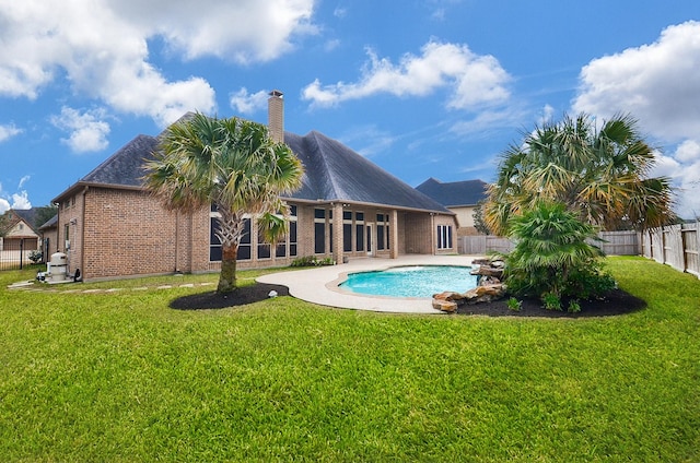 rear view of house with a fenced in pool and a yard