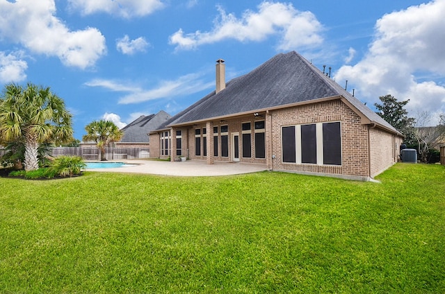 rear view of property featuring a fenced in pool, a yard, and a patio