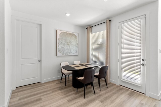 dining space featuring baseboards and light wood finished floors