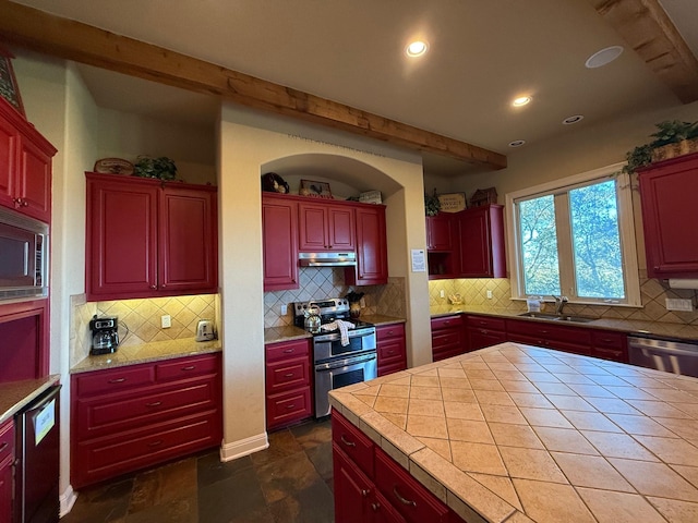 kitchen with stainless steel appliances, tasteful backsplash, sink, and tile countertops