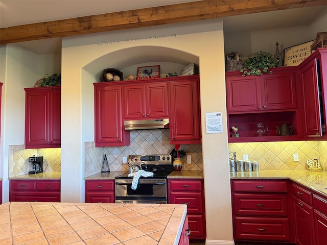 kitchen featuring stainless steel range with electric stovetop, backsplash, tile counters, and beamed ceiling