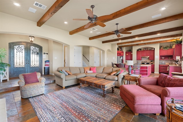 1017 Coventry Rd, Spicewood, TX 78669 - living area featuring arched walkways, stone tile flooring, beam ceiling, french doors, and ceiling fan