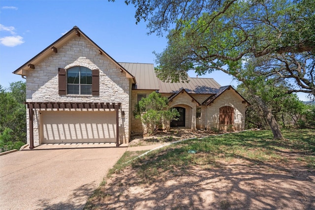 1017 Coventry Rd, Spicewood, TX 78669 - french provincial home featuring stone siding, a garage, concrete driveway, a standing seam roof, and metal roof