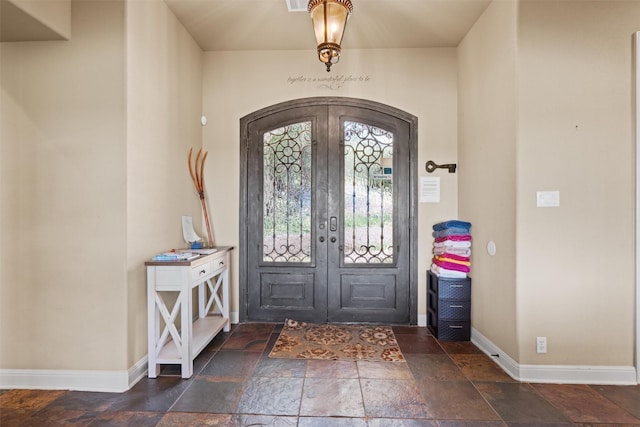 1017 Coventry Rd, Spicewood, TX 78669 - foyer entrance with stone tile flooring, arched walkways, baseboards, and french doors