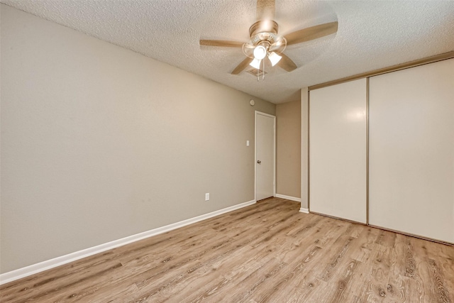 unfurnished bedroom with ceiling fan, a closet, a textured ceiling, and light wood-type flooring