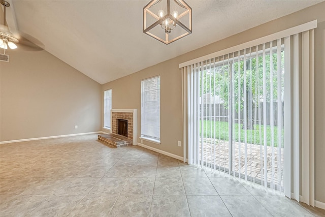 unfurnished living room with ceiling fan with notable chandelier, vaulted ceiling, a brick fireplace, and light tile patterned floors
