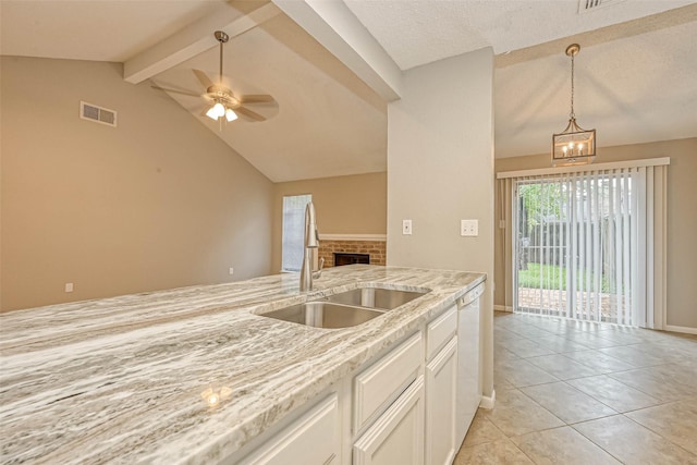 kitchen featuring a fireplace, lofted ceiling with beams, white cabinetry, sink, and light stone counters