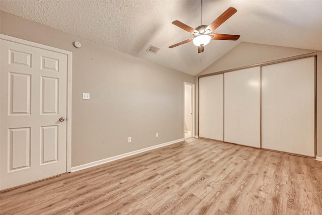 unfurnished bedroom featuring a closet, vaulted ceiling, light hardwood / wood-style flooring, and a textured ceiling