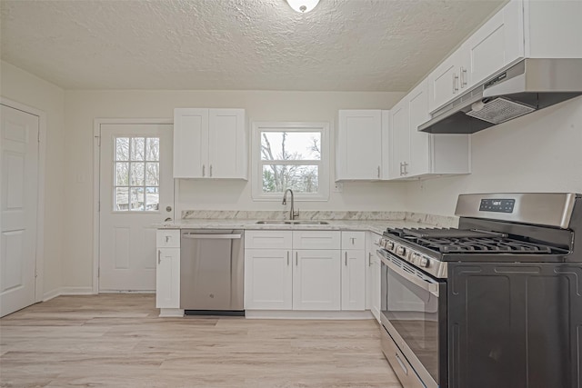 kitchen with sink, stainless steel appliances, white cabinetry, and light wood-type flooring