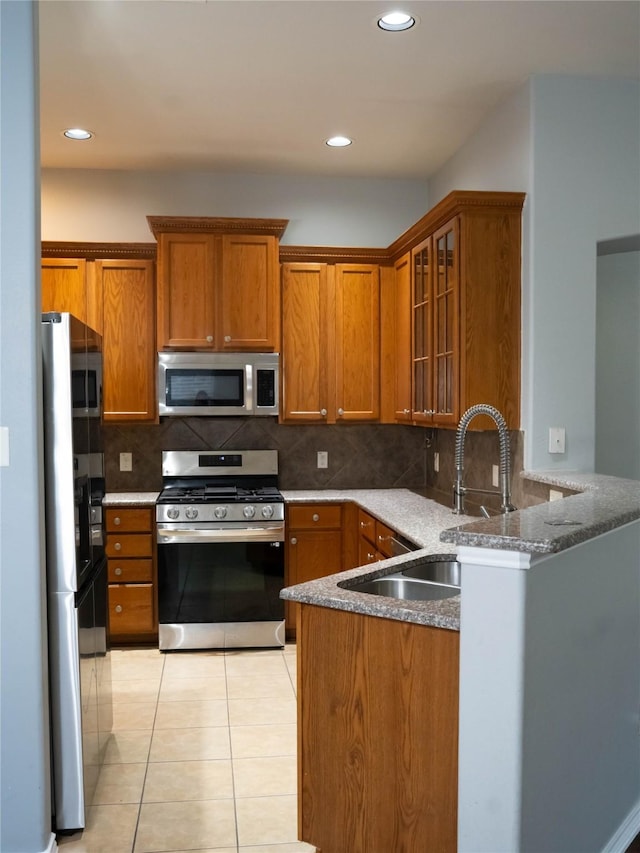 kitchen featuring appliances with stainless steel finishes, kitchen peninsula, sink, and decorative backsplash