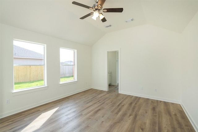 empty room with lofted ceiling, hardwood / wood-style floors, and ceiling fan