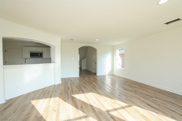 unfurnished living room featuring sink and light hardwood / wood-style flooring