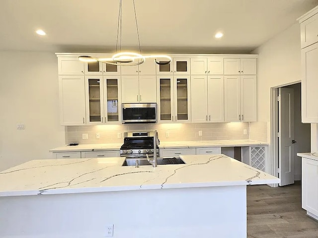 kitchen with light stone countertops, appliances with stainless steel finishes, pendant lighting, and white cabinets