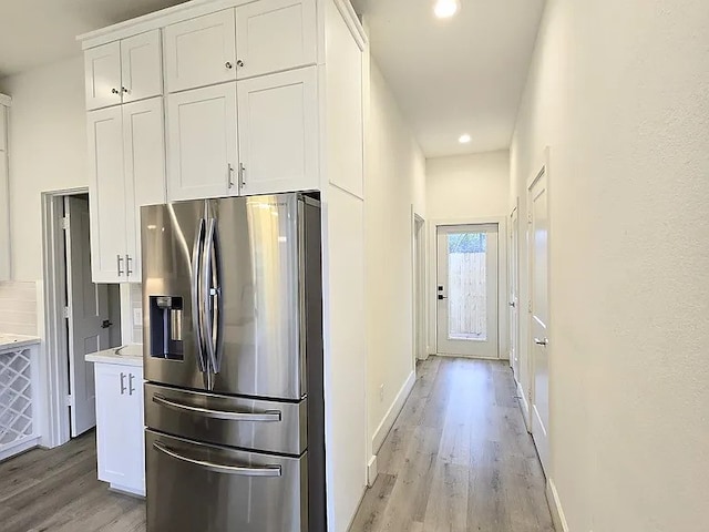 kitchen featuring white cabinetry, stainless steel fridge, light hardwood / wood-style floors, and tasteful backsplash