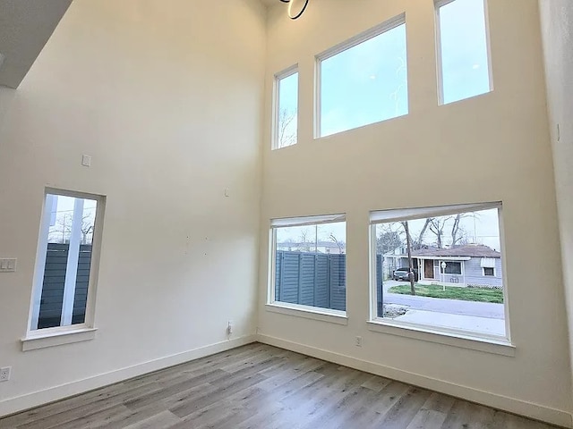 unfurnished room with a towering ceiling and light wood-type flooring