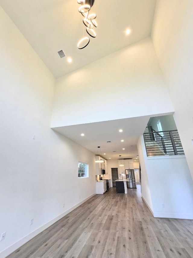 unfurnished living room with a high ceiling and light wood-type flooring