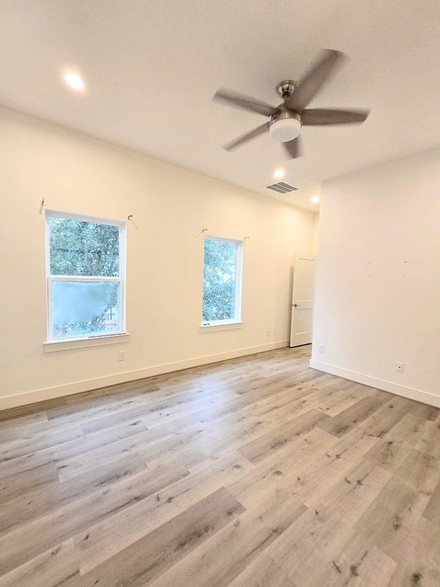 empty room with a wealth of natural light, ceiling fan, and light wood-type flooring