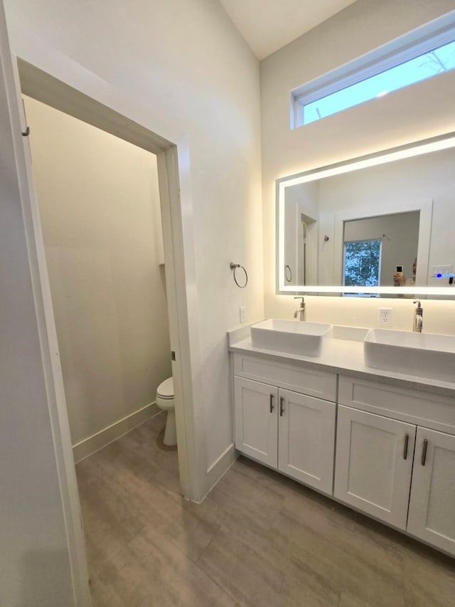 bathroom with hardwood / wood-style flooring, vanity, and toilet