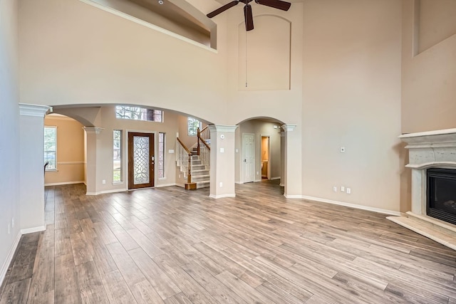 unfurnished living room with decorative columns, wood-type flooring, and ceiling fan