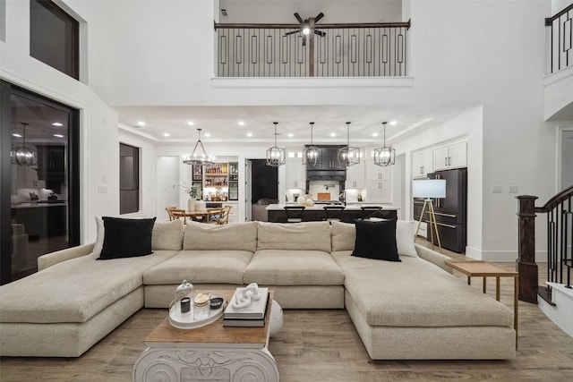 living area featuring light wood-style flooring, a high ceiling, and a chandelier