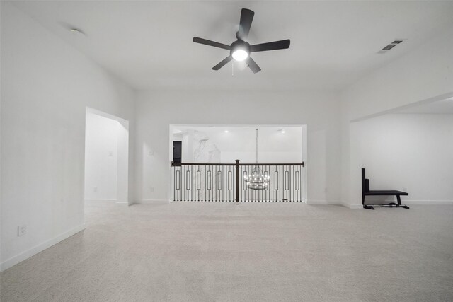 carpeted spare room with baseboards, visible vents, and ceiling fan with notable chandelier