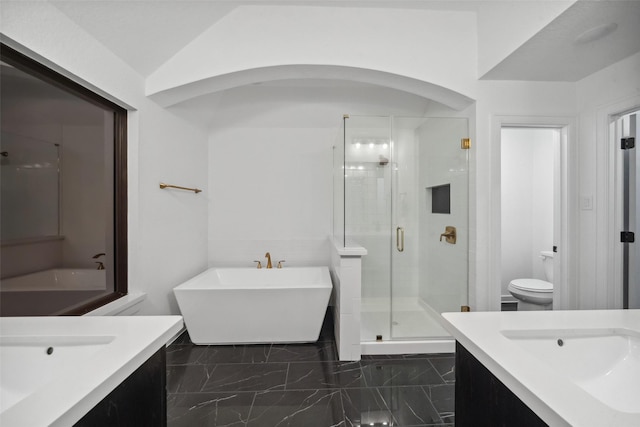 bathroom featuring two vanities, marble finish floor, a freestanding bath, a shower stall, and a sink