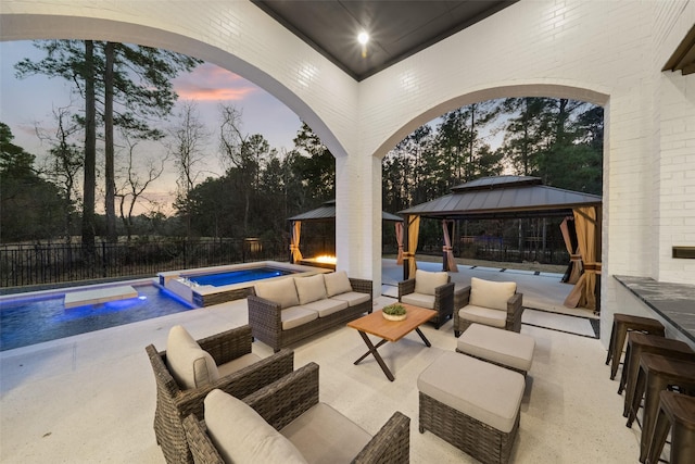 patio terrace at dusk with a fenced in pool, an in ground hot tub, fence, a gazebo, and an outdoor living space