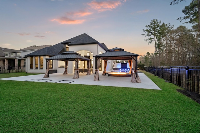 back of property at dusk with a yard, a gazebo, and a patio