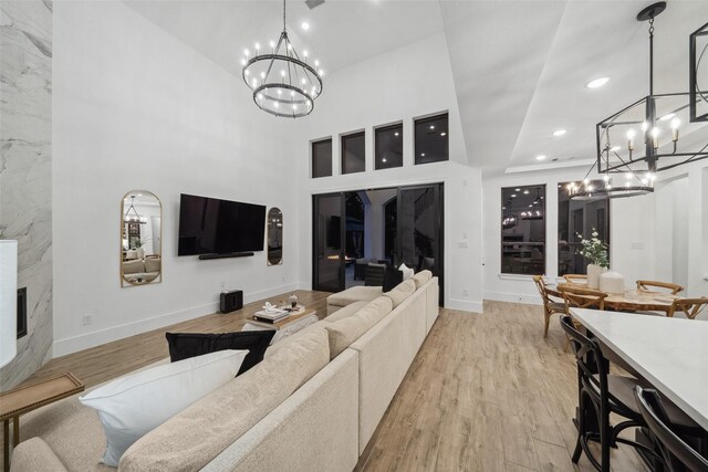 living area with recessed lighting, an inviting chandelier, light wood-style floors, a high end fireplace, and baseboards