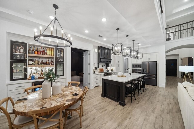 kitchen featuring light wood-style flooring, appliances with stainless steel finishes, arched walkways, and light countertops