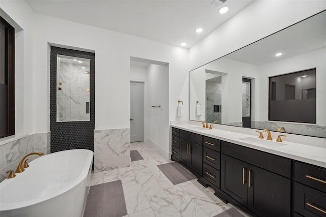 bathroom with marble finish floor, a marble finish shower, a sink, and a soaking tub