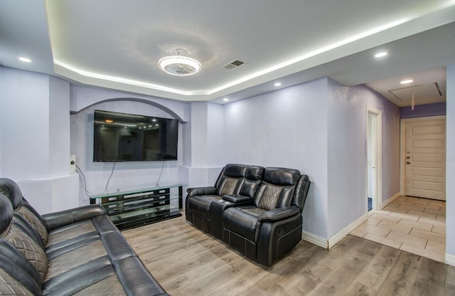 living room with a tray ceiling and light hardwood / wood-style flooring