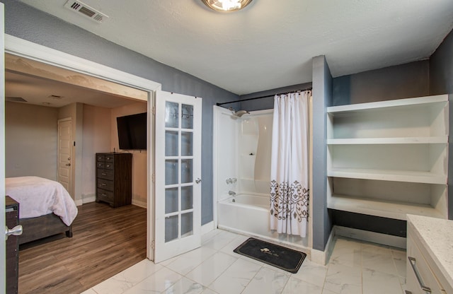 bathroom featuring french doors, vanity, shower / bathtub combination with curtain, and a textured ceiling