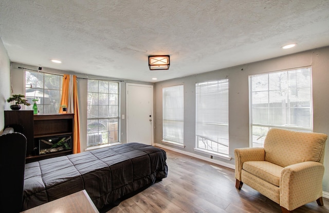 bedroom with multiple windows, hardwood / wood-style floors, and a textured ceiling