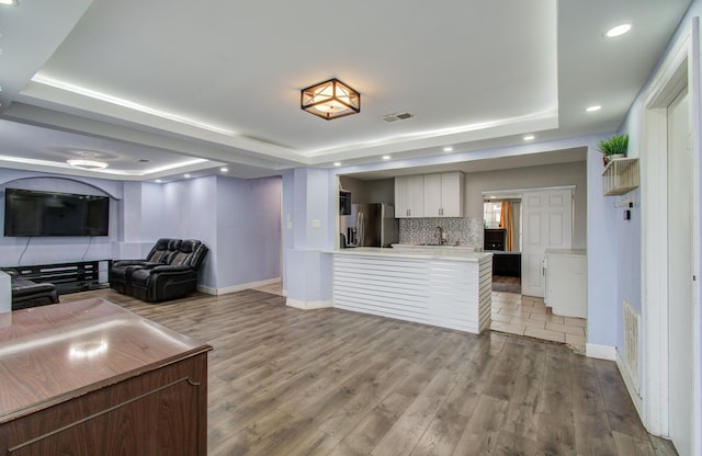 unfurnished living room with a raised ceiling, wood-type flooring, and sink